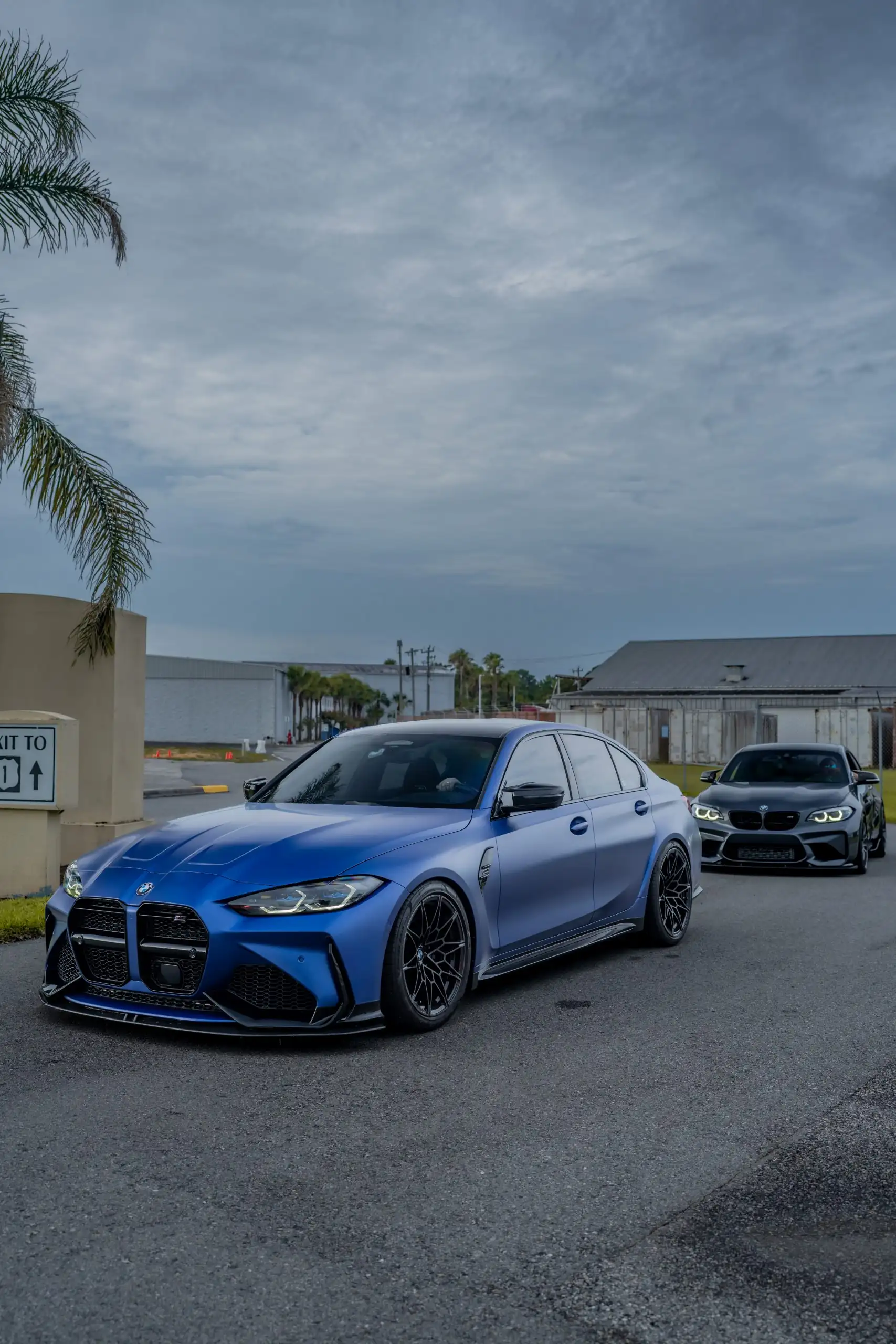 Blue BMW M3 at a Staker Productions show under a storm sky